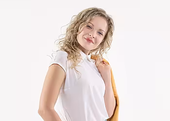 Moderátorka v bílé blůze a džínách pózuje na světlém pozadí.
