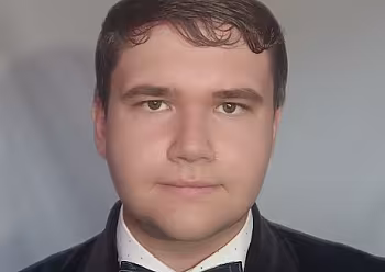 Moderátor ve smokingu s motýlkem na neutrálním pozadí.