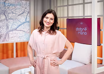 Moderátorka Michaela Casková v růžových šatech stojí v kulisách Dobrého rána České televize.