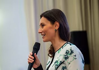 Moderátorka Michaela Casková v květinových šatech s mikrofonem.