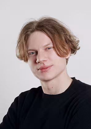 Moderátor v černém tričku na světlém pozadí.
